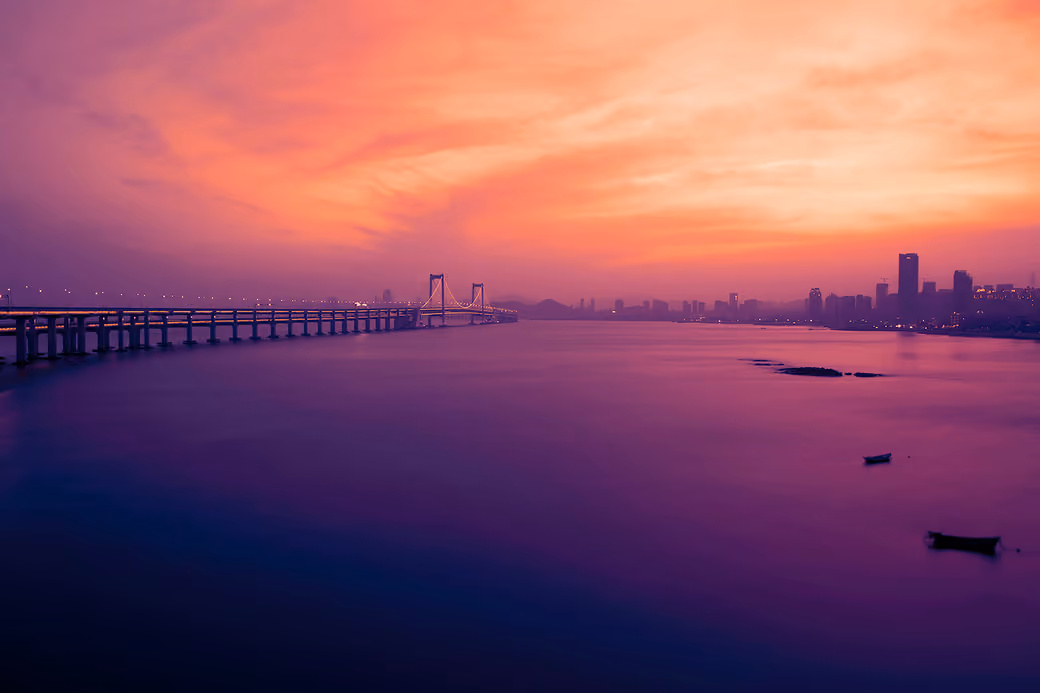 Xinghai Bridge at sunset over ocean — desktop and phone wallpaper, free download