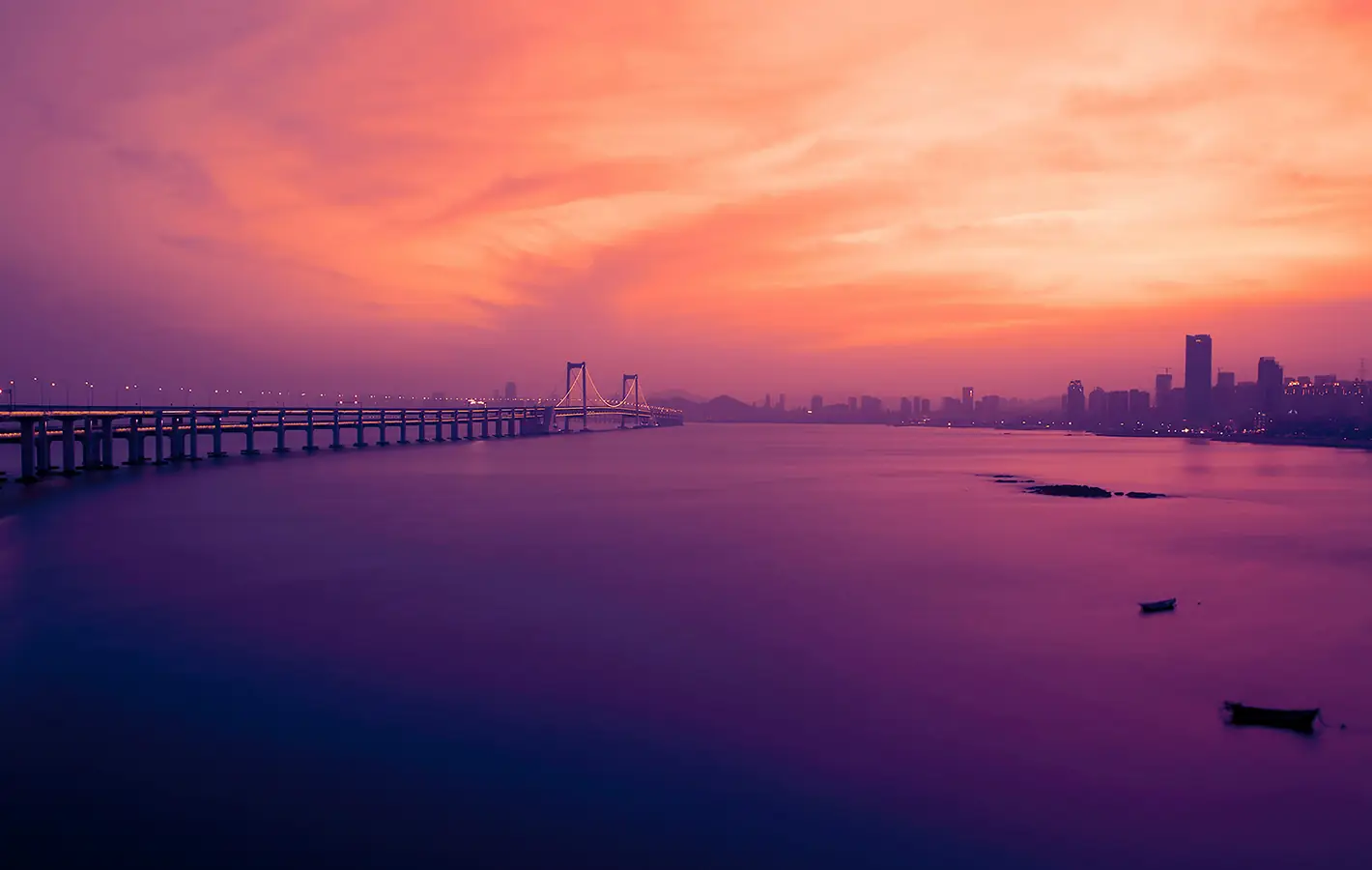 Xinghai Bridge at sunset over ocean — desktop and phone wallpaper, free download