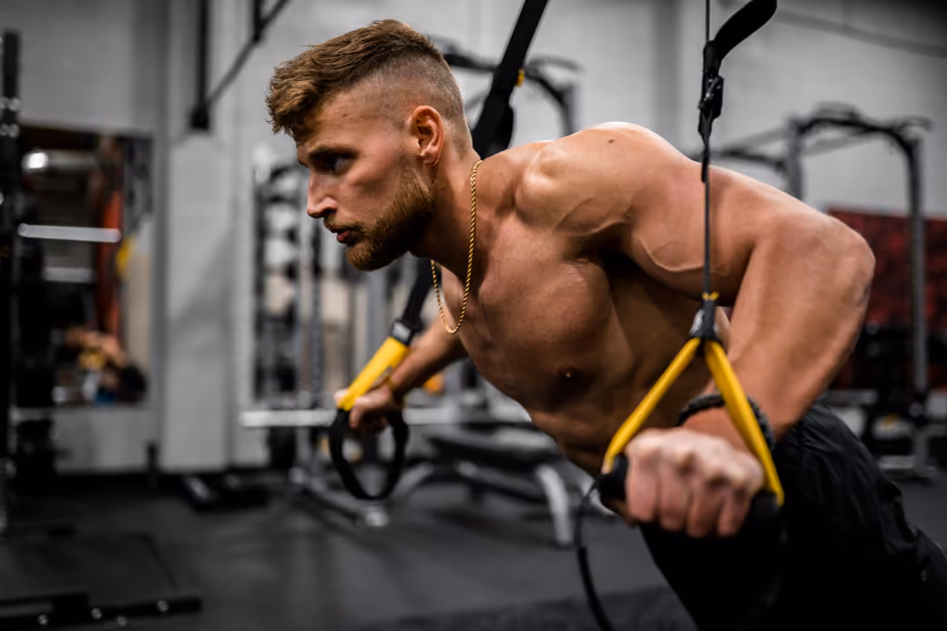 Muscular man working out with TRX straps — desktop and phone wallpaper, free download