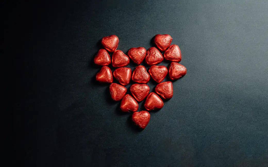 Red heart-shaped chocolates arranged in a heart — desktop and phone wallpaper, free download