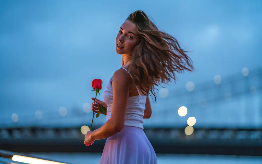 Woman holding rose near riverside — desktop and phone wallpaper, free download