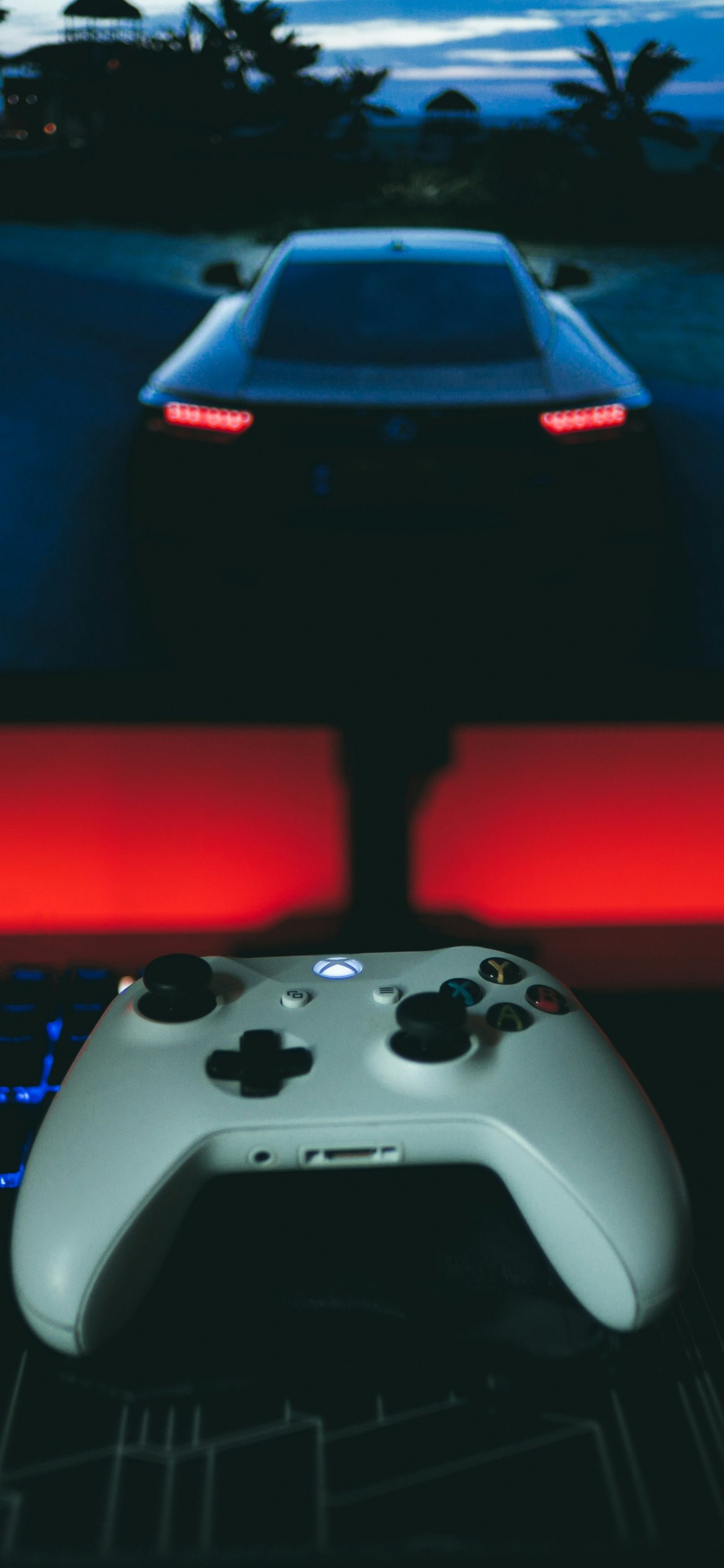 Контроллер Xbox перед гоночной игрой - Обои для iPhone 12 Pro/13 Pro/14 в разрешении 1170x2532