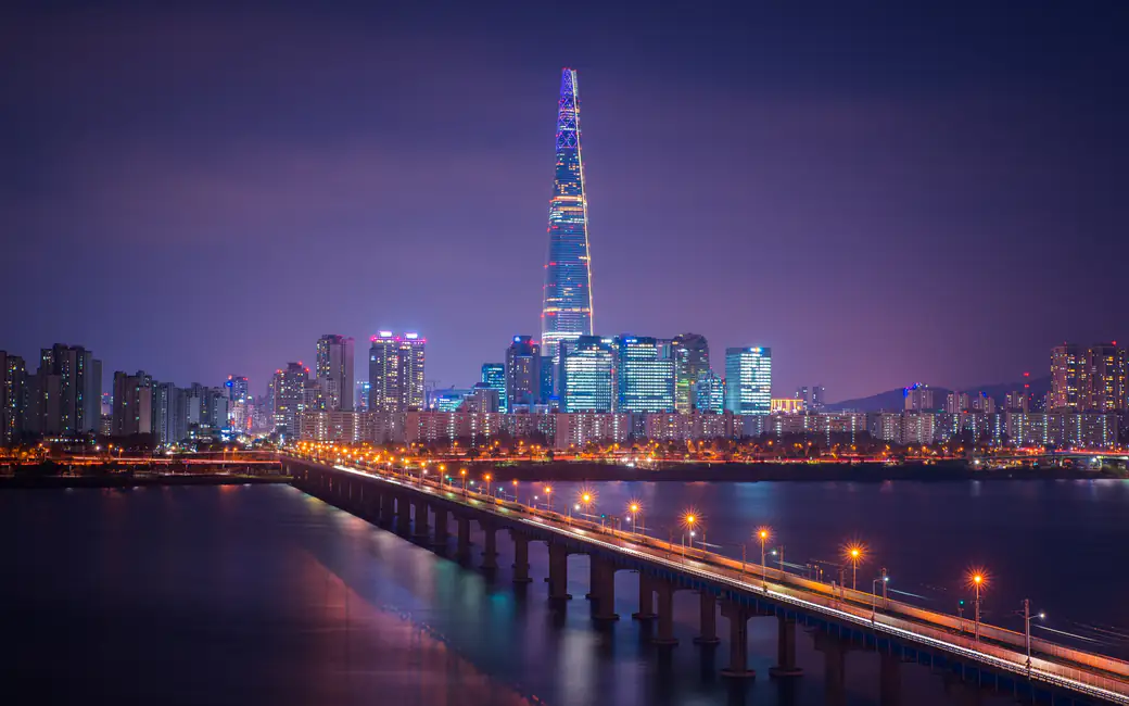 Lotte Tower illuminated in Seoul nighttime cityscape — desktop and phone wallpaper, free download