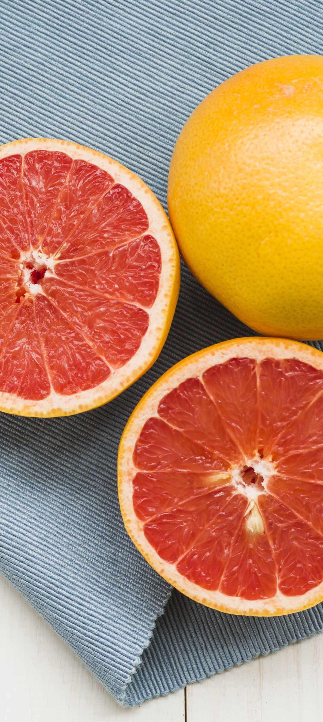 Sliced grapefruit on blue cloth - Wallpapers for Samsung Galaxy A13/A14/A53, Realme 12 Pro 5G, POCO M5 in 1080x2408 resolution