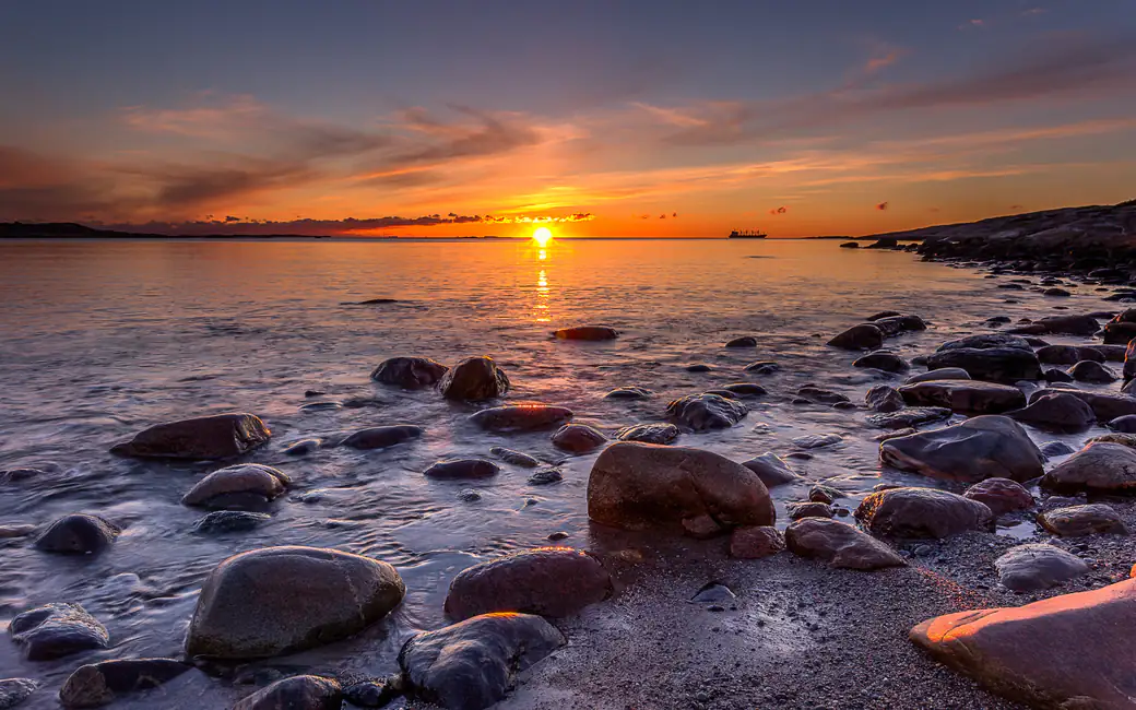 Rocky shore in a yellow sunset — desktop and phone wallpaper, free download