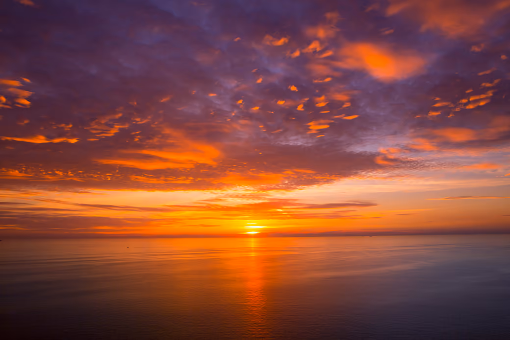 Orange sunset over a calm sea — desktop and phone wallpaper, free download